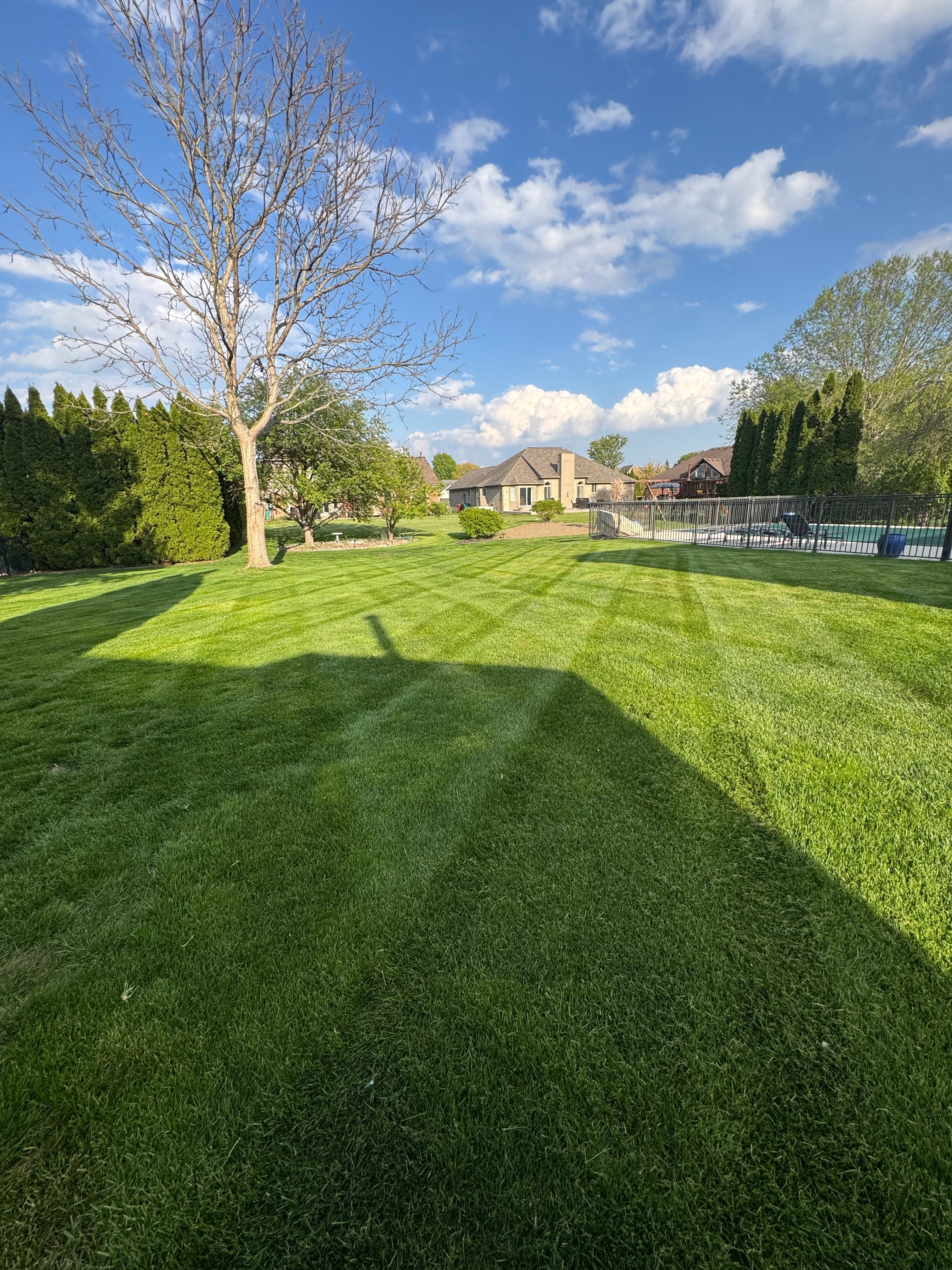 Professional lawn mowing with wide stripe pattern across large residential backyard in Macomb County Michigan